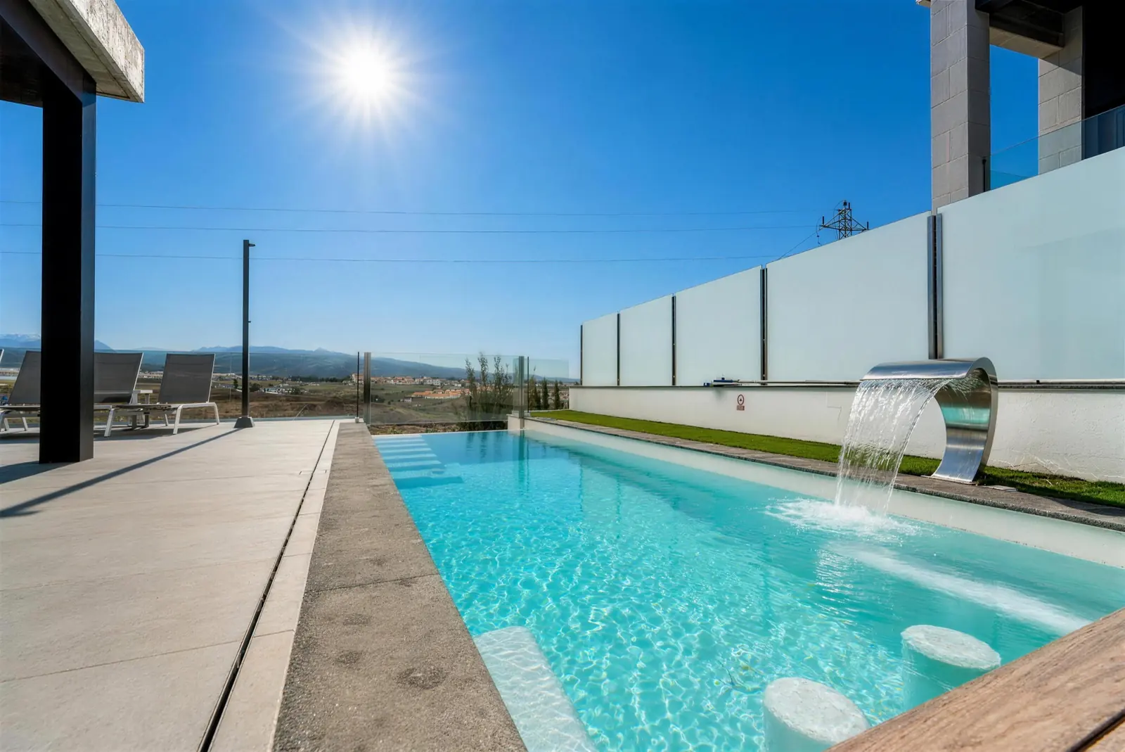 Privatpool mit Edelstahl-Wasserfall und Sitzen im Wasser, Berge im Hintergrund