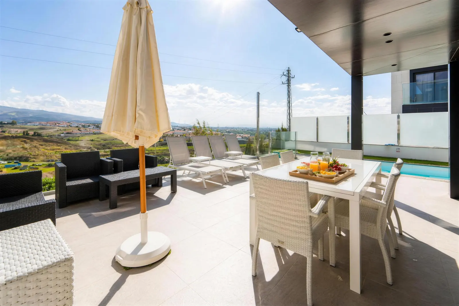 Essbereich unter dem Vordach, Rattansofas und Liegen mit Bergblick