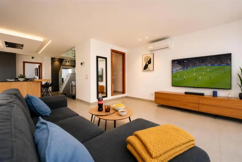 Salón con sofá gris, mesas de centro de madera y televisor grande